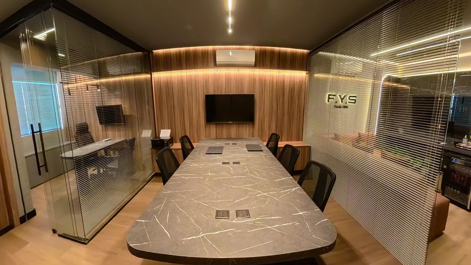 Sala de reunião da F.Y.S com mesa ampla e divisórias de vidro