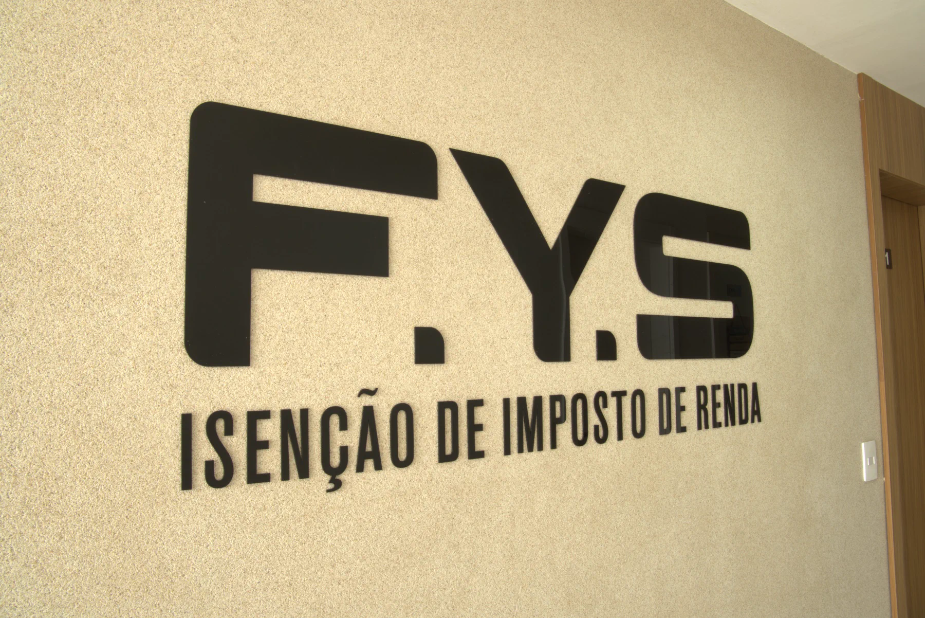Logotipo F.Y.S Isenção de Imposto de Renda na parede do escritório